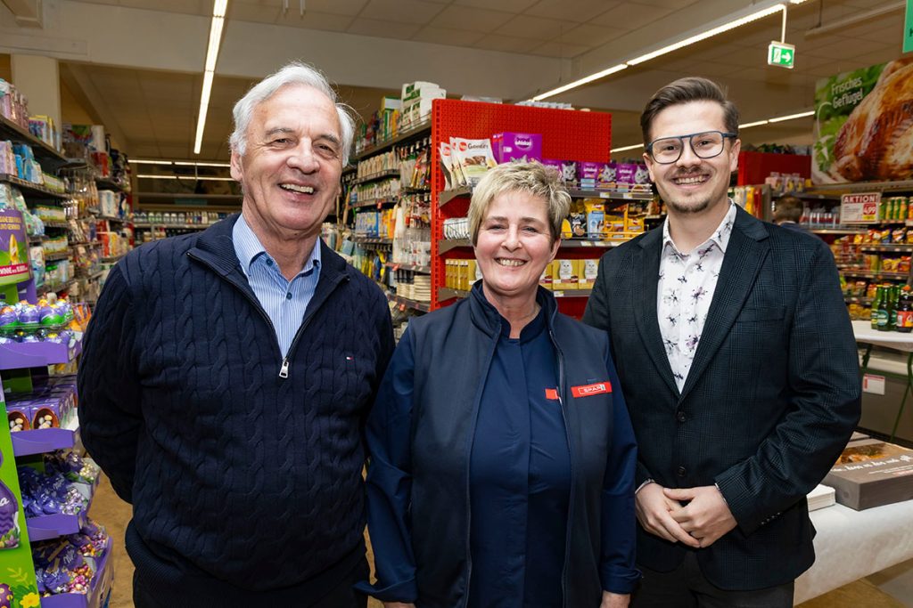 Drei Personen stehen im Verkaufsbereich des SPAR-Marktes Rottenmann und lächeln in die Kamera. In der Mitte steht die Marktleiterin, neben ihr zwei Gäste der Eröffnungsfeier. Im Hintergrund sind Regale mit verschiedenen Lebensmitteln und Aktionsaufsteller zu sehen.