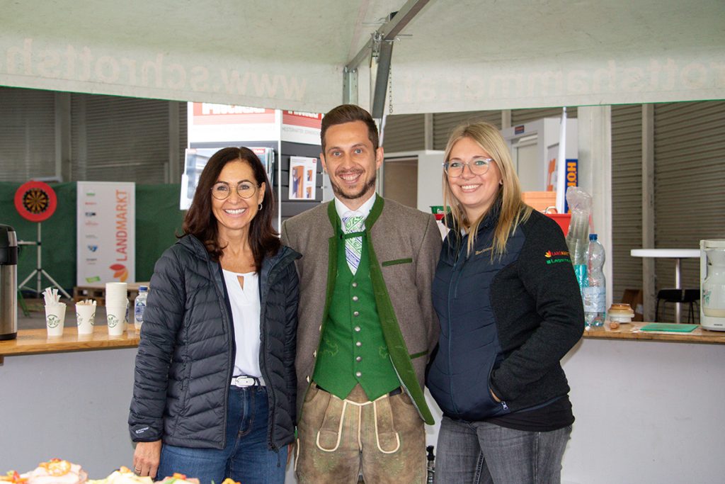 Drei Mitarbeiter*innen der Landmarkt Lagerhaus Baustoffe stehen gemeinsam vor einem Bewirtungsbereich beim Kompetenztag für Profis in Aigen.