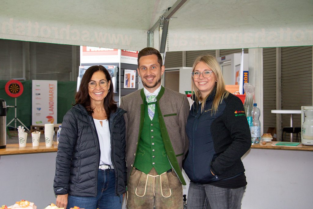 Drei Mitarbeiter*innen der Landmarkt Lagerhaus Baustoffe stehen gemeinsam vor einem Bewirtungsbereich beim Kompetenztag für Profis in Aigen.