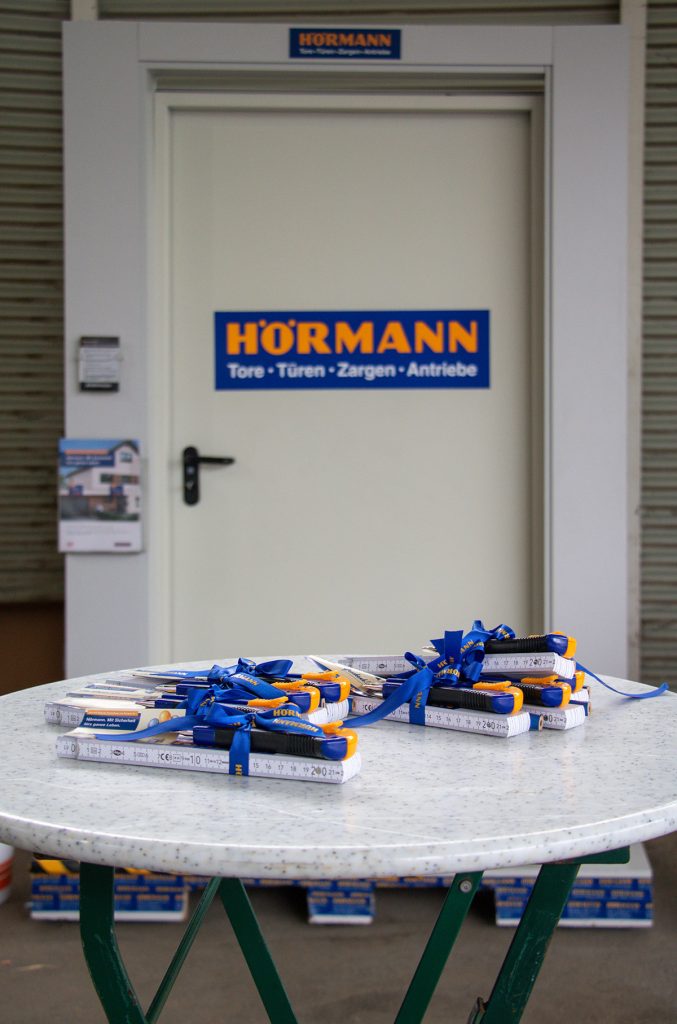 Werbematerialien und kleine Giveaways von Hörmann liegen auf einem Tisch vor einer ausgestellten Tür beim Kompetenztag für Profis in Aigen.